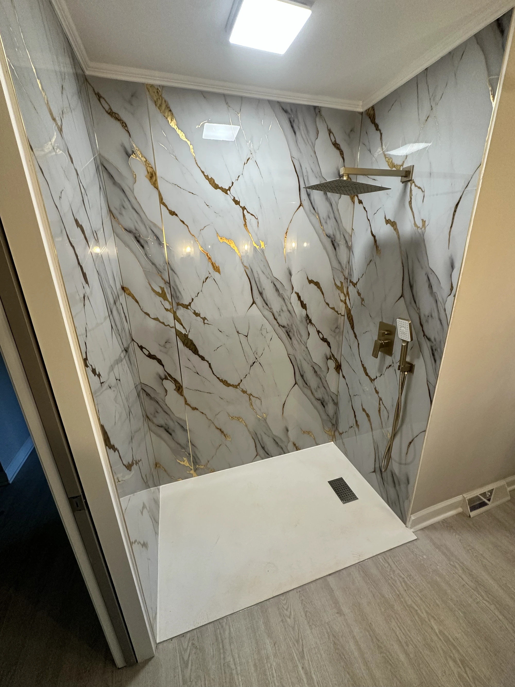M22 Construction aging-in-place renovation — marble walk-in shower with bench seat