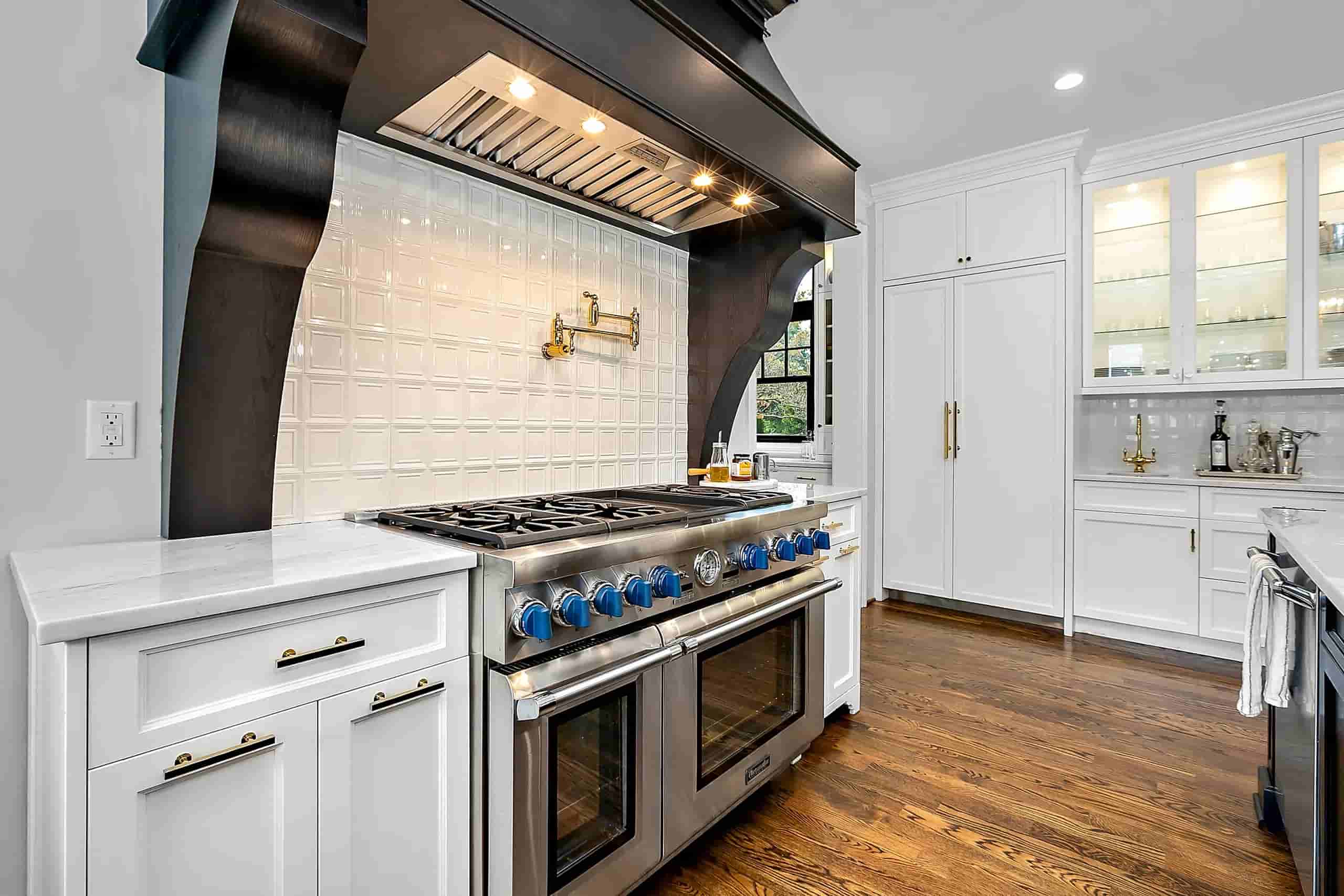 M22 Construction finished kitchen remodel with custom range hood, marble counters, and white cabinetry