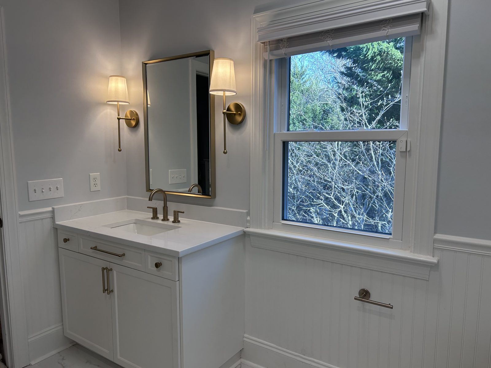 M22 Construction bathroom remodel in Charlotte with white shaker vanity, quartz counter, and brushed-gold fixtures